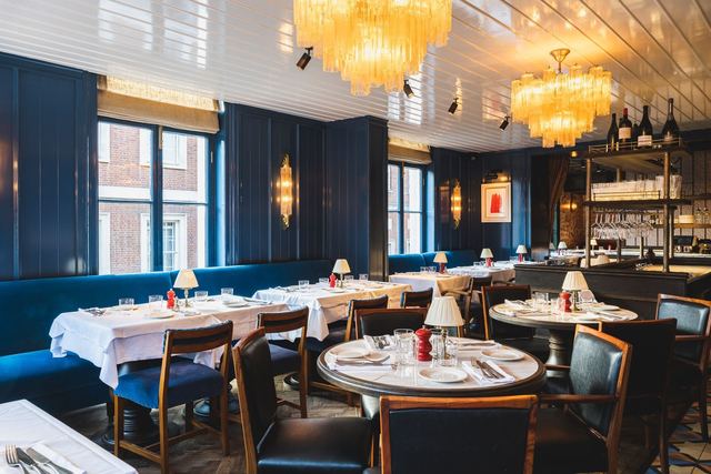 The dining room of The Thomas Cubitt: navy panelling, velvet banquettes and Murano chandeliers