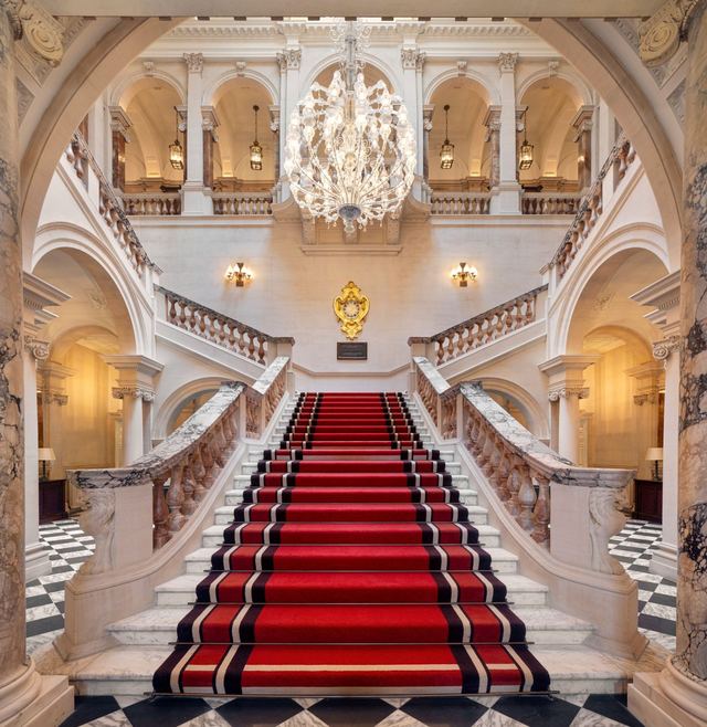 The red-carpeted marble grand staircase at Raffles London at The OWO