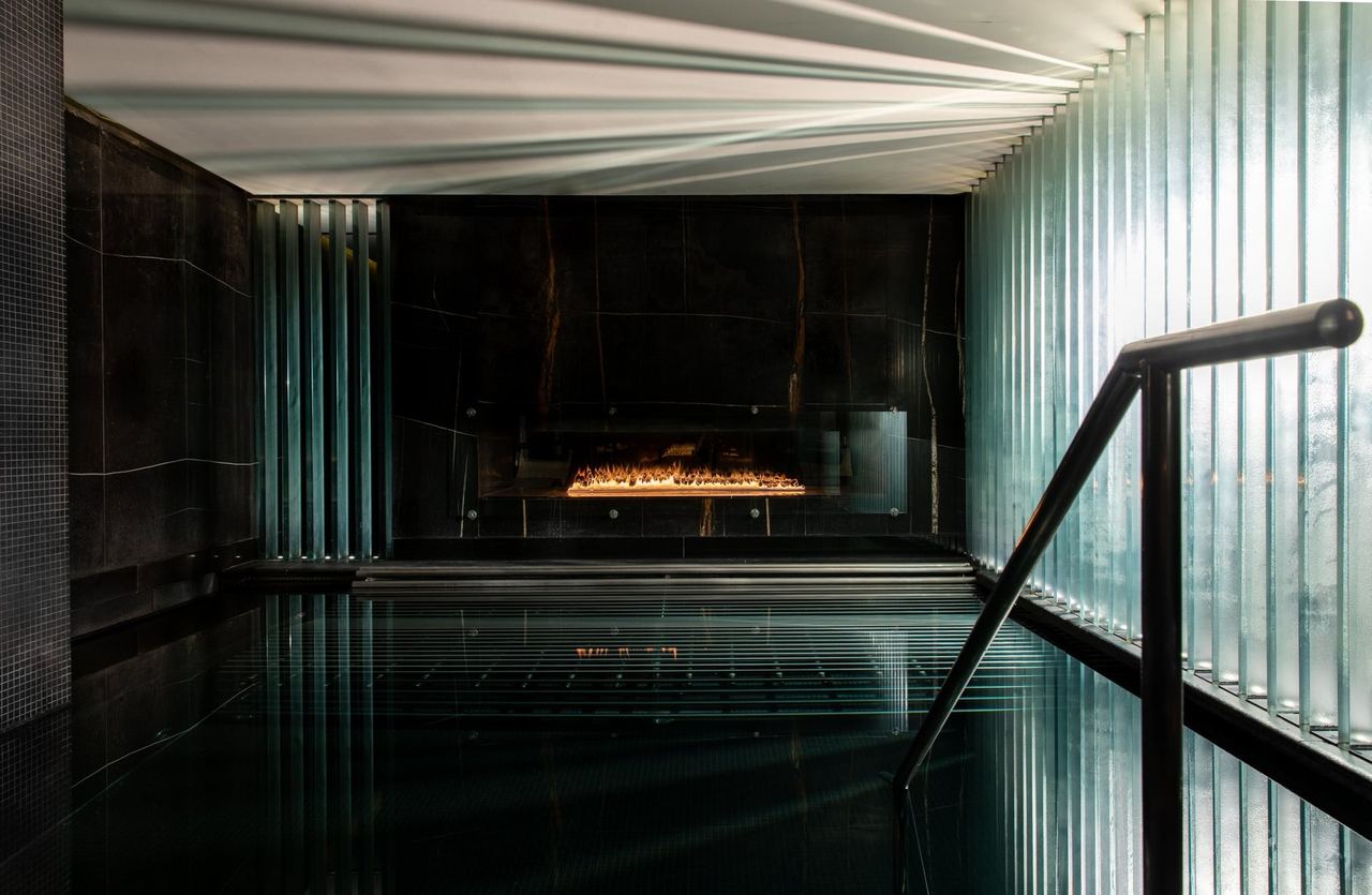 The dark, fire-lit pool at Biome by Corinthia London